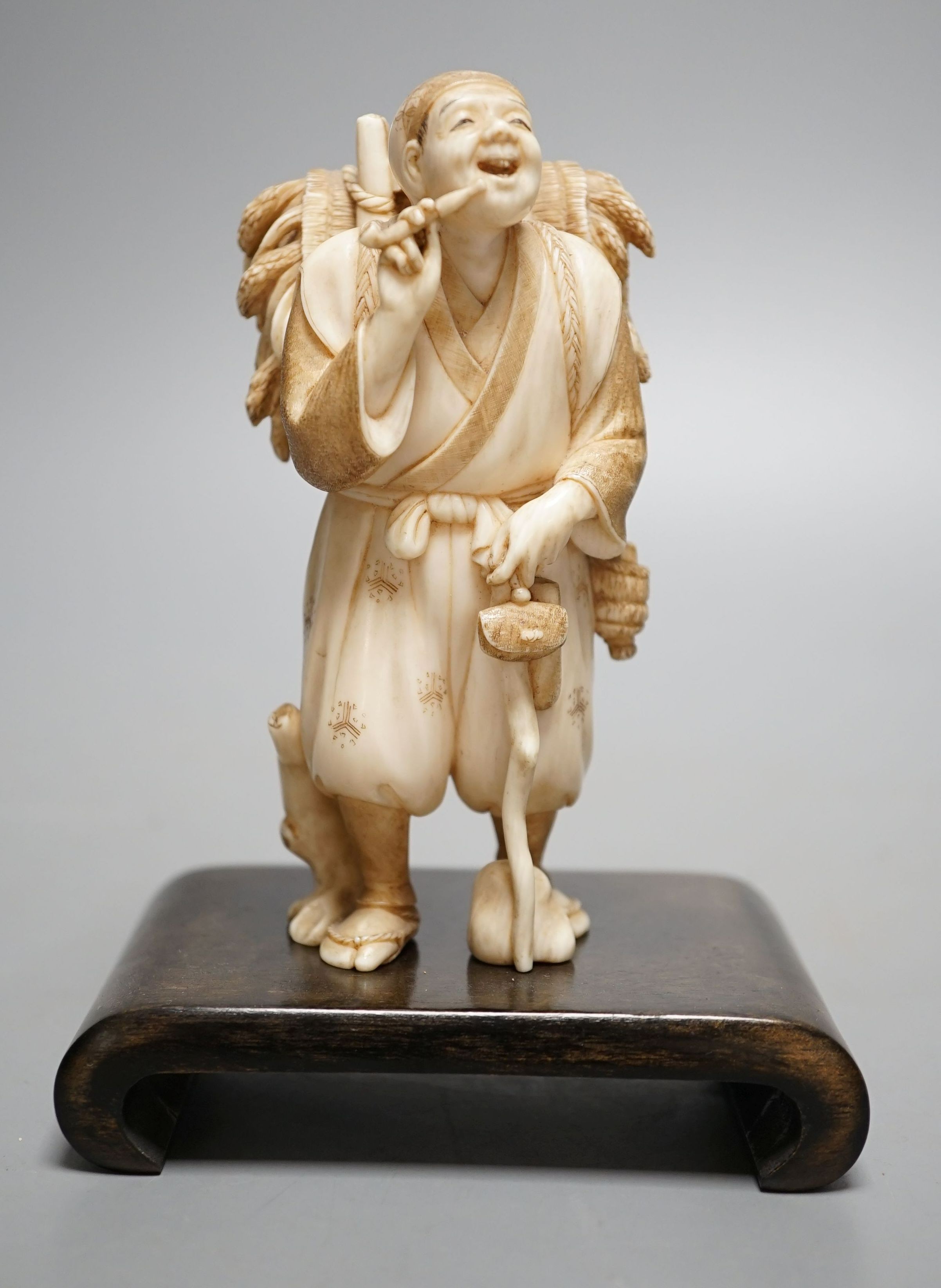 A Japanese ivory figure of a farmer smoking a pipe, Meiji period, signed - 12cm tall